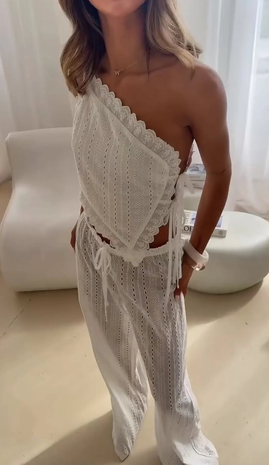 Ensemble deux pièces blanc avec broderie ajourée, composé d’un haut court asymétrique à nouer et d’un pantalon à jambes larges