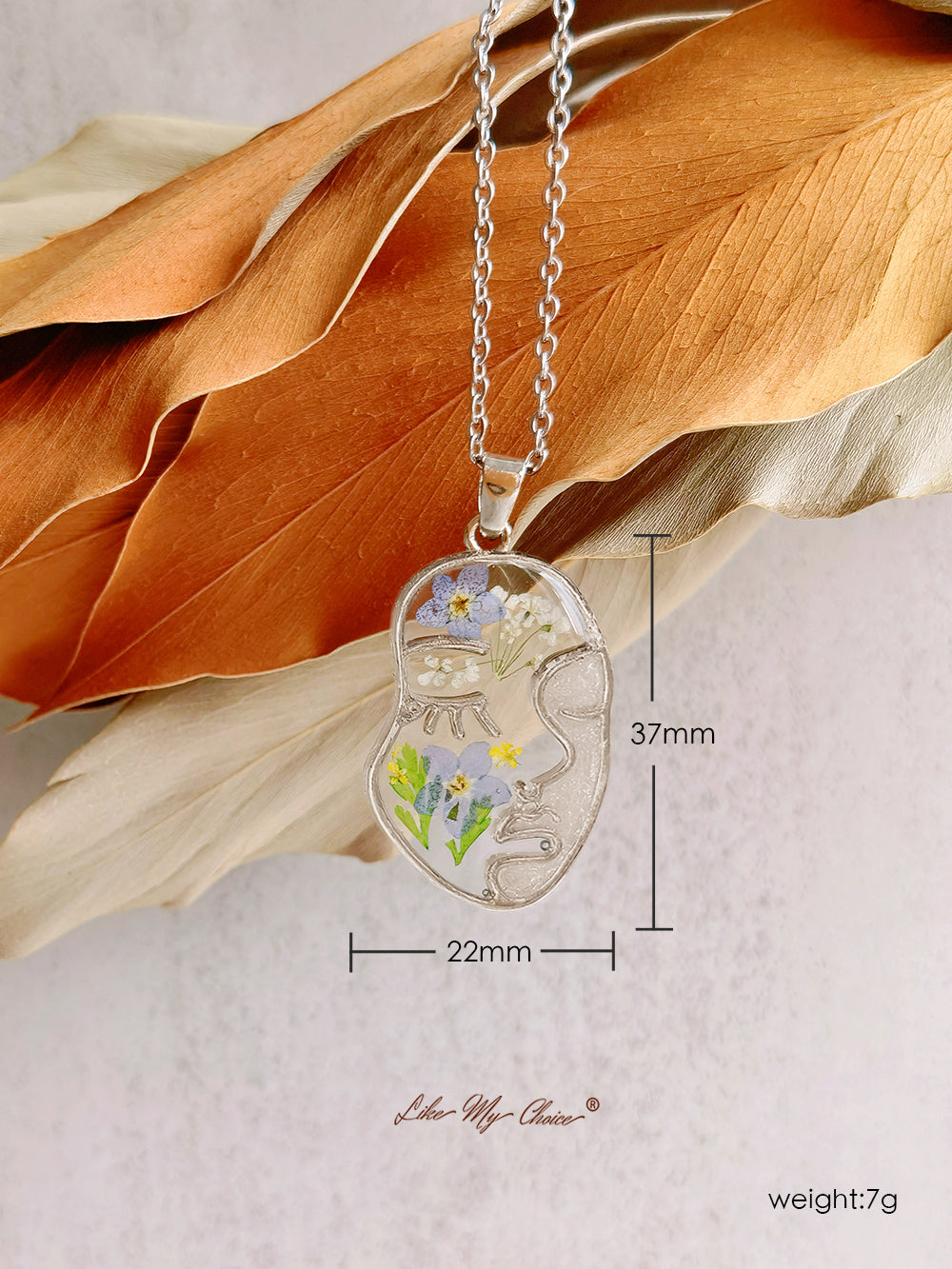Collana con non ti scordar di me pressati in resina e volto astratto