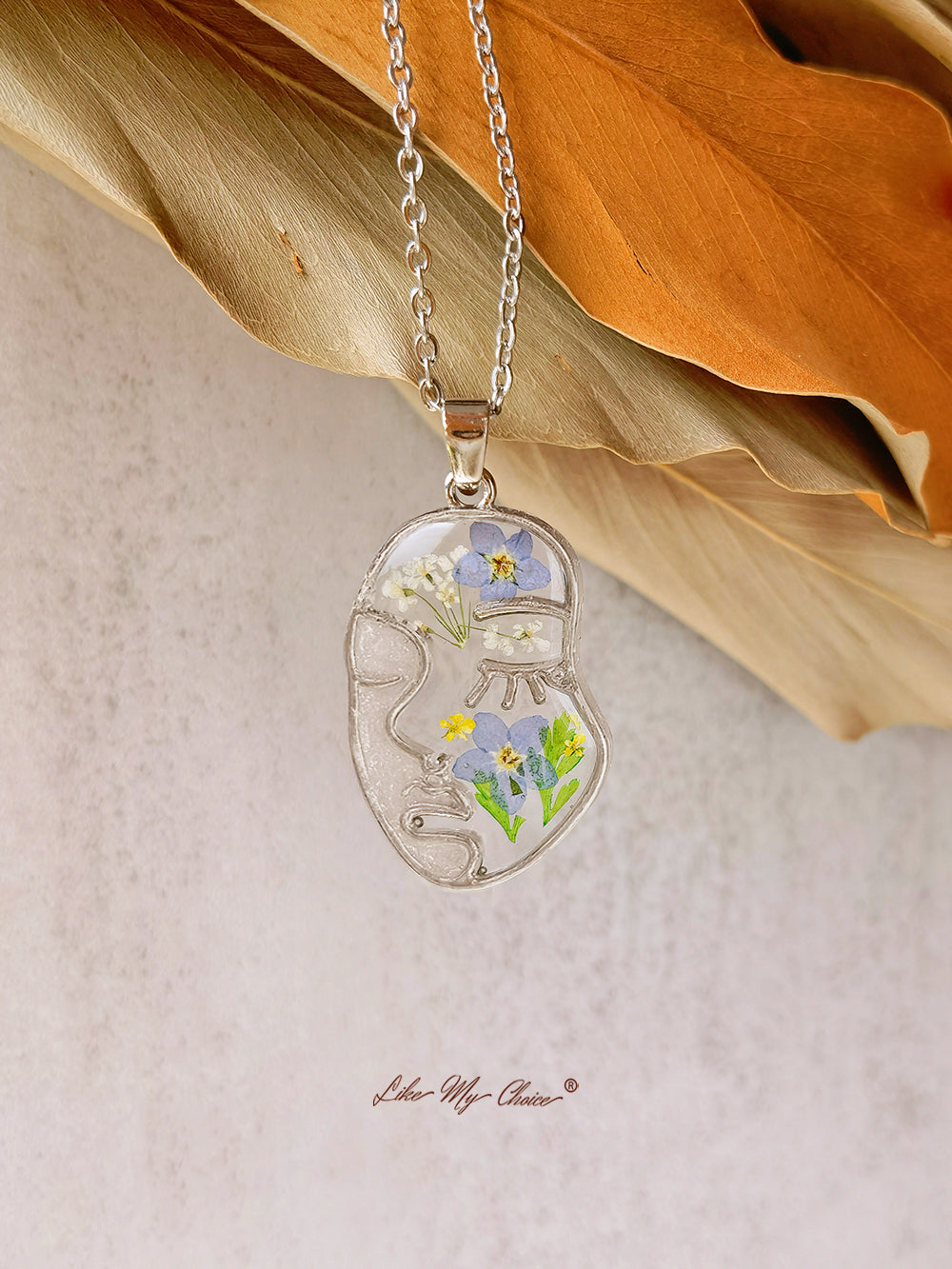 Collana con non ti scordar di me pressati in resina e volto astratto