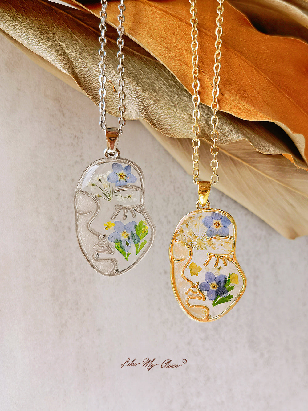 Collana con non ti scordar di me pressati in resina e volto astratto