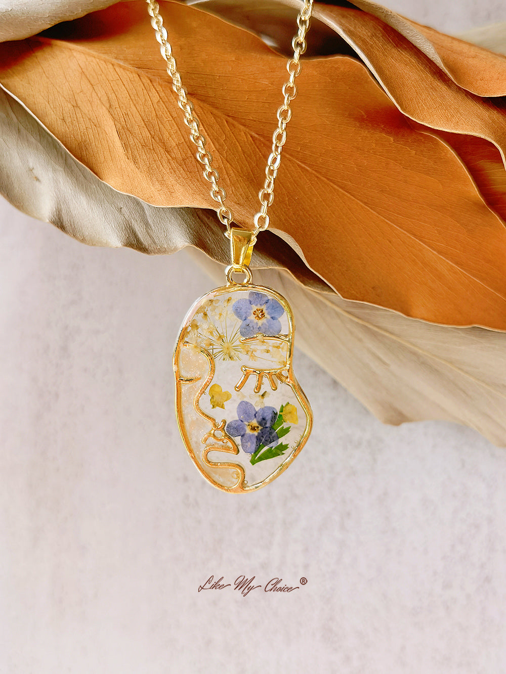 Collana con non ti scordar di me pressati in resina e volto astratto