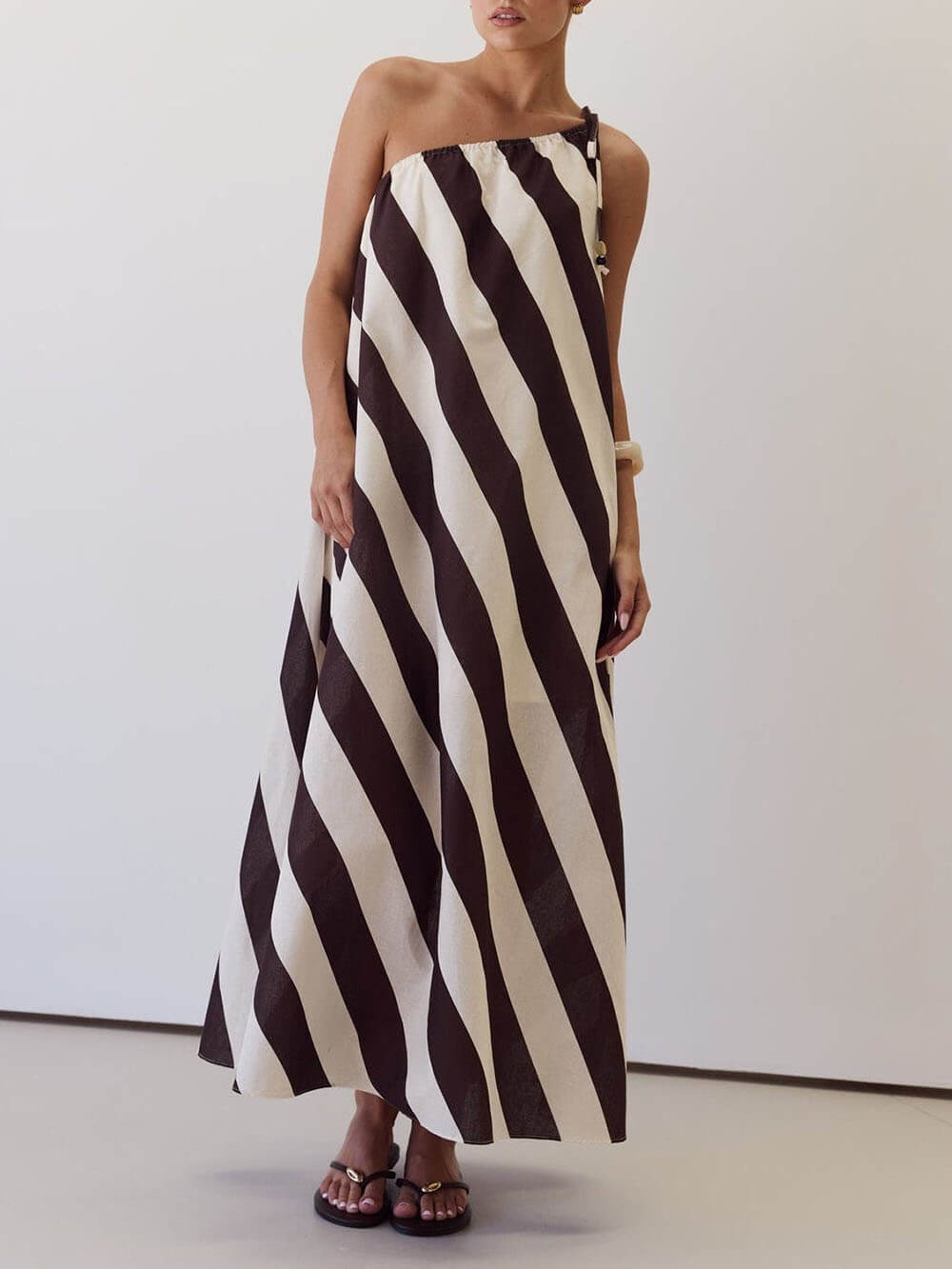 Vestido maxi elegante às riscas, estampado, com um ombro descoberto, laço na cintura e bolsos laterais