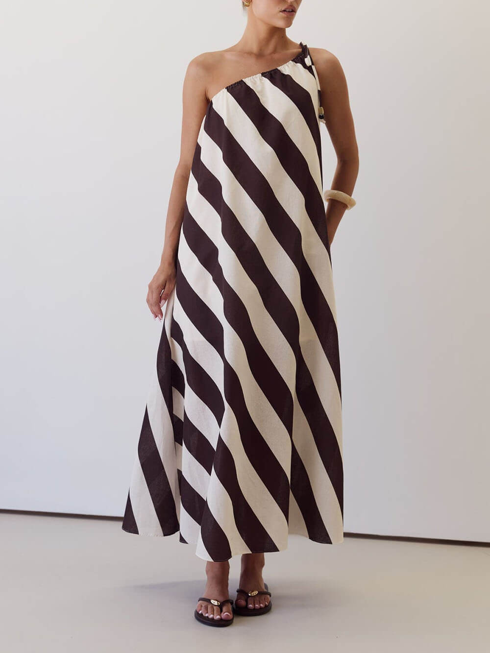 Vestido maxi elegante às riscas, estampado, com um ombro descoberto, laço na cintura e bolsos laterais