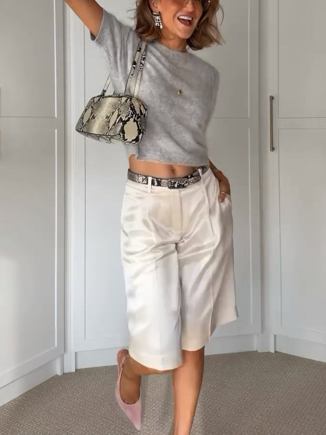 Zweiteiliges Outfit aus grauem Stricktop mit Raglanärmeln und weißer Satinhose mit weitem Bein