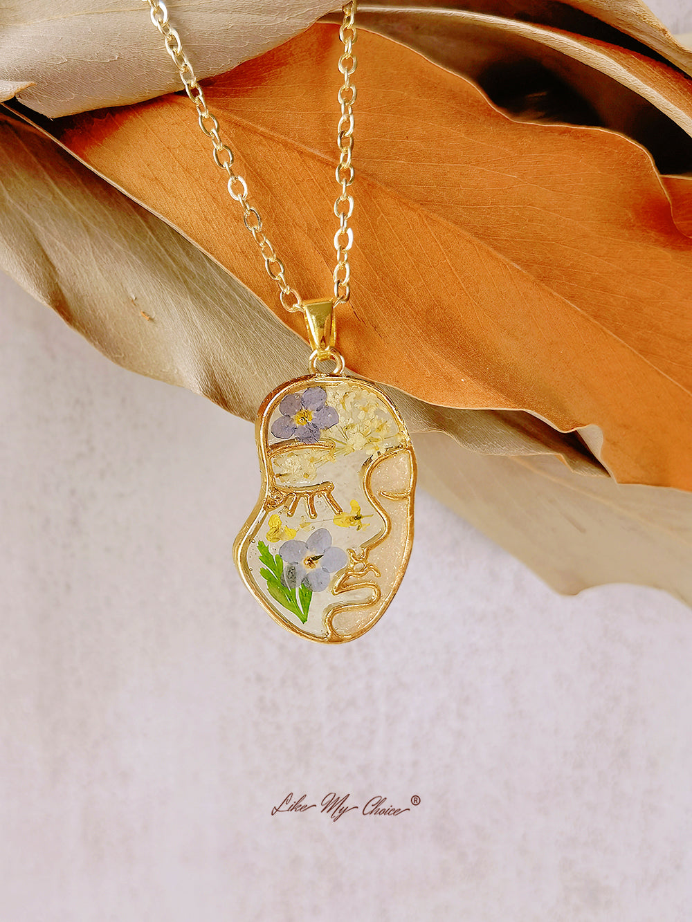 Collana con non ti scordar di me pressati in resina e volto astratto