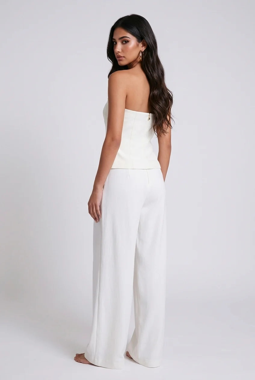 Completo bianco a due pezzi con gilet senza spalline e bottoni sul davanti e pantaloni plissettati a gamba ampia